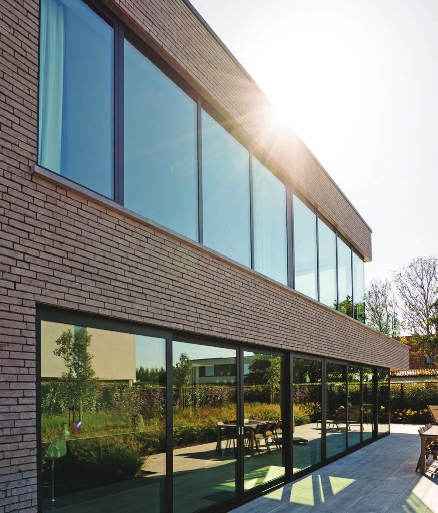Fenêtres en bandeau à châssis aluminium noir sur façade en brique