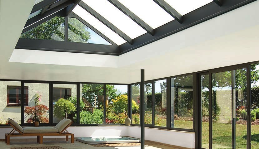 Intérieur de véranda avec toiture vitrée ouvert sur le jardin